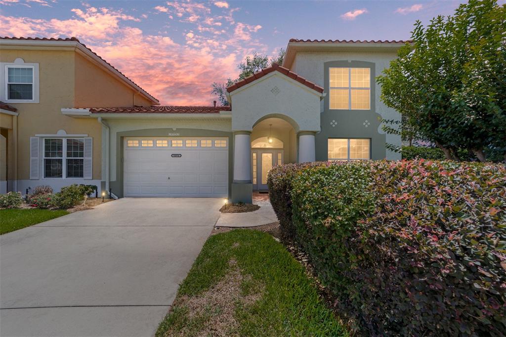 A two-story house with a garage, a covered entryway, and a large hedge in front — 1074 AVENIDA SONOMA, LADY LAKE, FL
