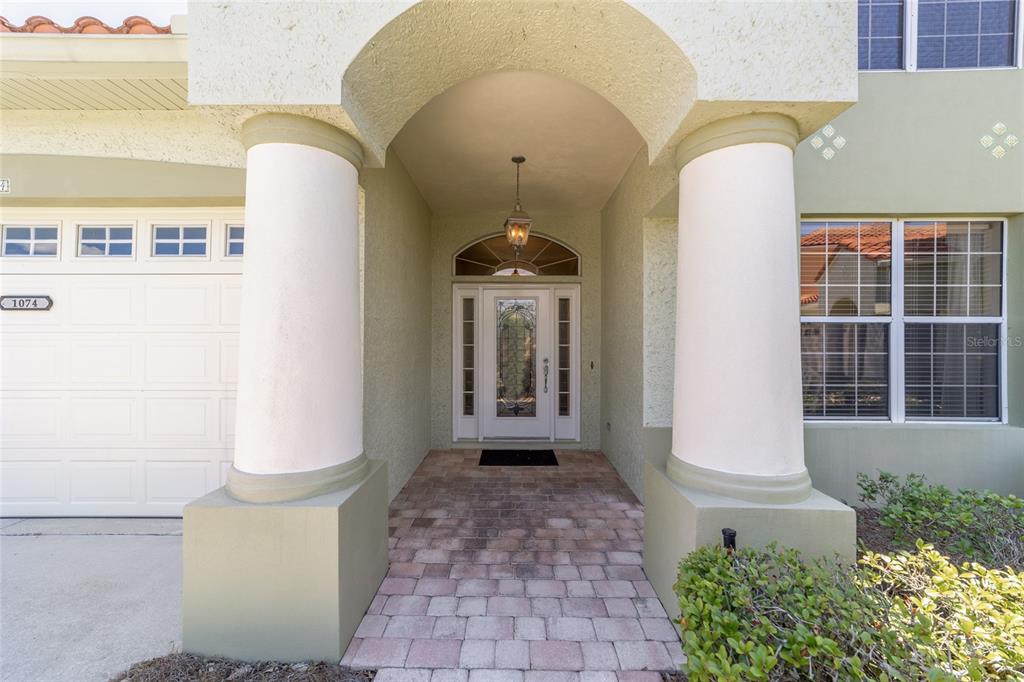 The exterior of a house features a covered entryway with two columns and a door — 1074 AVENIDA SONOMA, LADY LAKE, FL