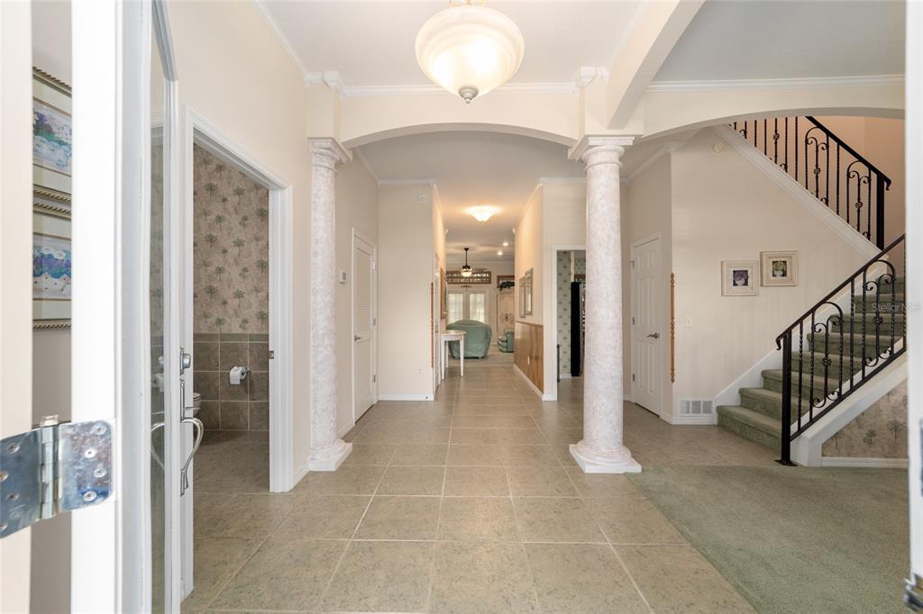 A tiled foyer features two decorative columns, a staircase with a railing, and arched entryways — 1074 AVENIDA SONOMA, LADY LAKE, FL