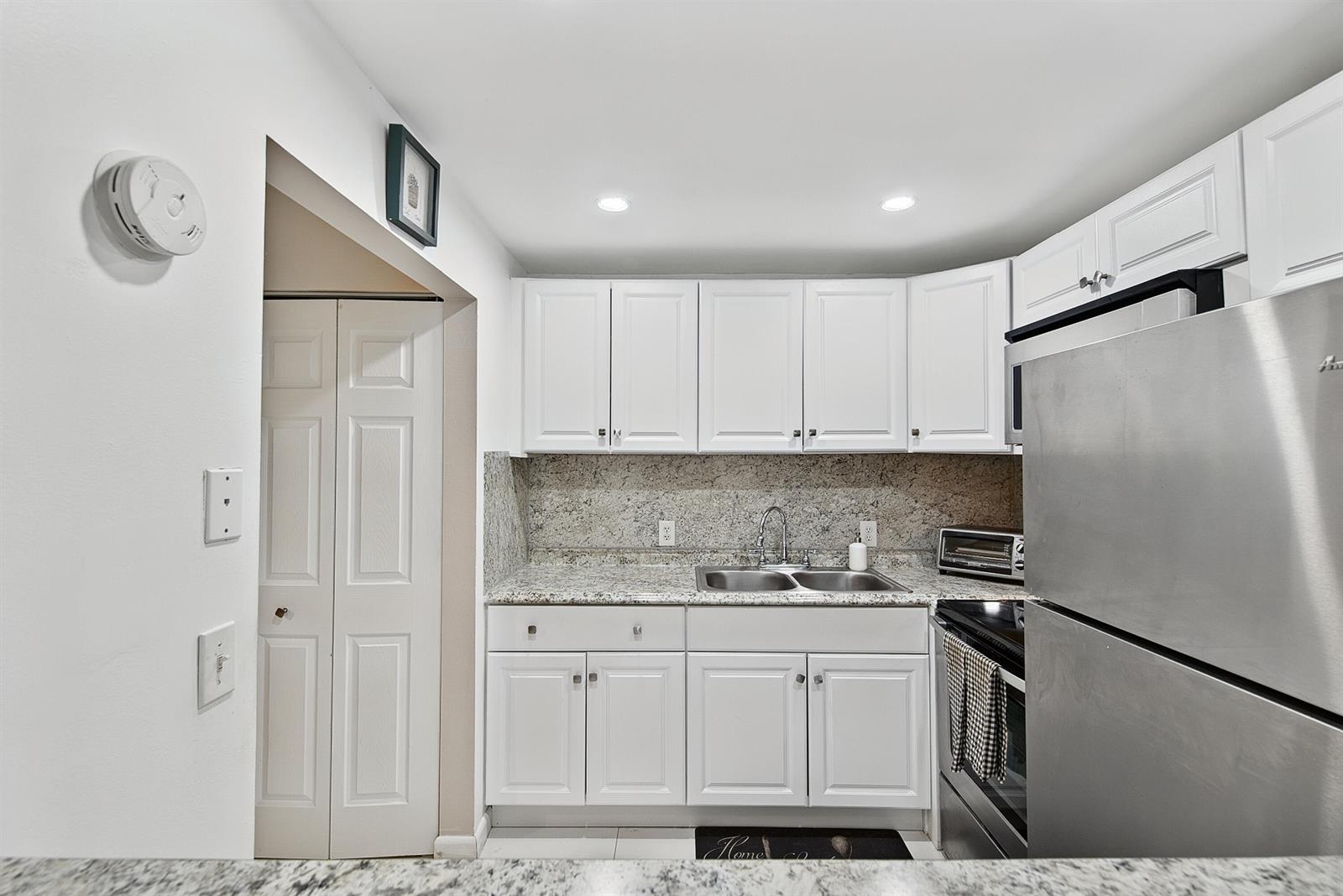 A kitchen features white cabinets, granite countertops, stainless steel appliances, and a double sink — 96 Fanshaw C, Boca Raton FL 33434, BOCA RATON, FL