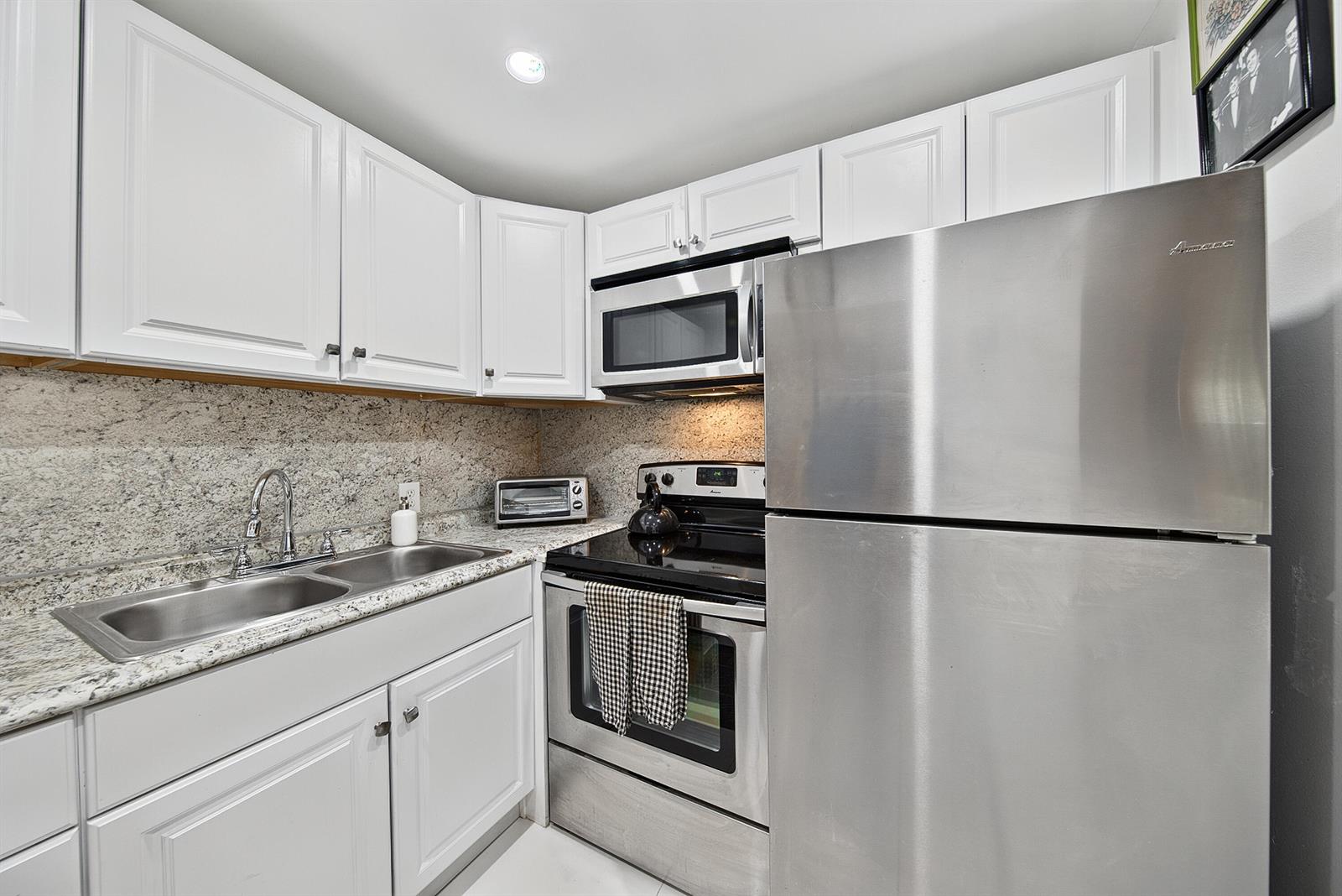 A kitchen features white cabinets, granite countertops, and stainless steel appliances — 96 Fanshaw C, Boca Raton FL 33434, BOCA RATON, FL