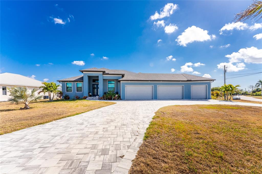 A blue single-story house with a three-car garage and a paved driveway — 401 ALBATROSS ROAD, ROTONDA WEST, FL