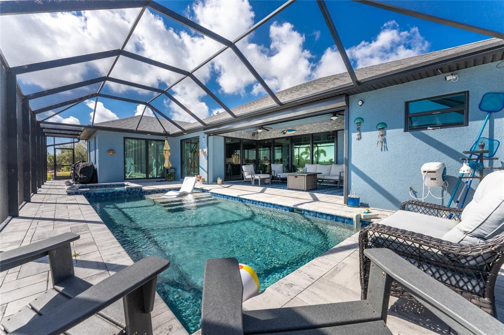 A screened-in patio features a swimming pool with a sun shelf and outdoor seating — 401 ALBATROSS ROAD, ROTONDA WEST, FL