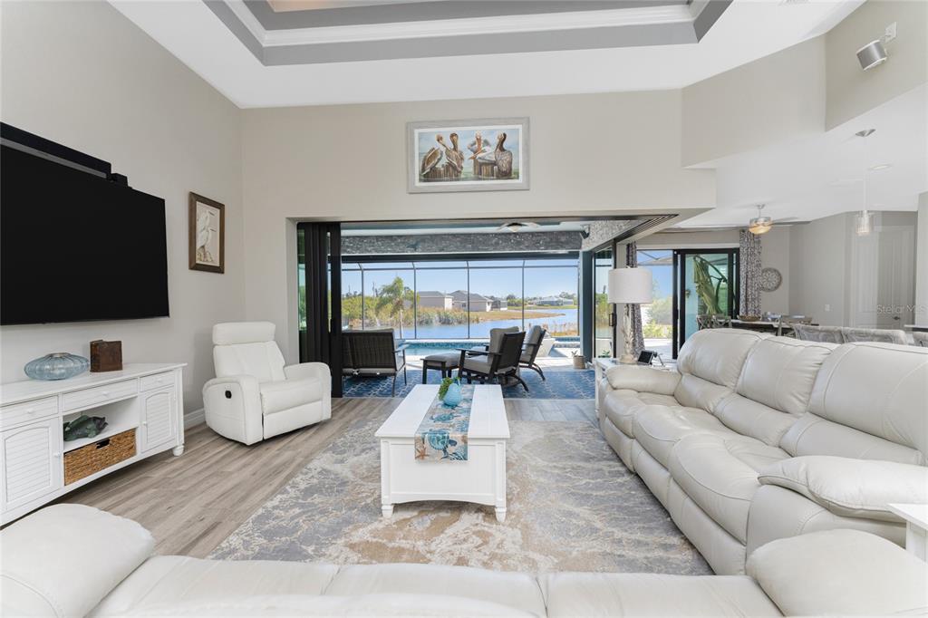 A living room with white leather furniture, a coffee table, and sliding doors to a pool — 401 ALBATROSS ROAD, ROTONDA WEST, FL