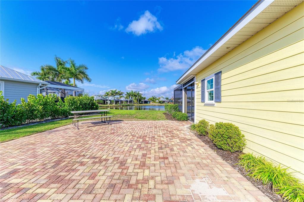 A yellow house with a brick patio overlooks a pond and palm trees — 8144 SW BIMINI WAY LOT 64, ARCADIA, FL