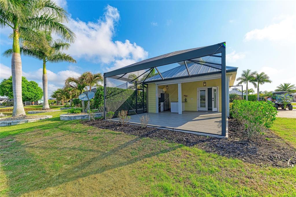 A yellow house with a screened-in patio sits on a grassy lawn with palm trees — 8144 SW BIMINI WAY LOT 64, ARCADIA, FL