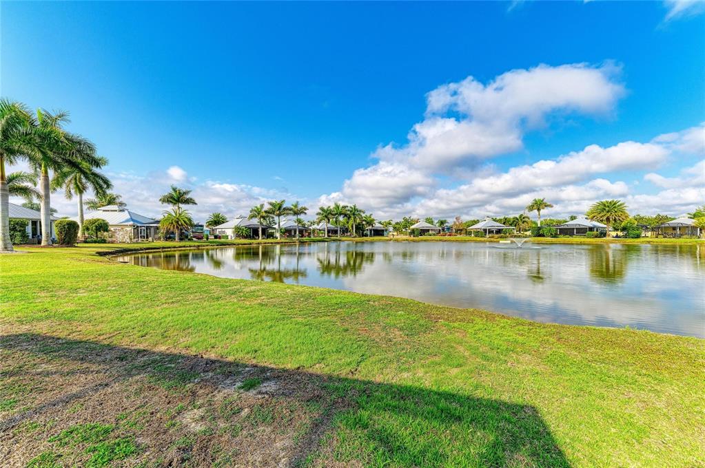 A grassy lawn overlooks a pond surrounded by palm trees and several residential houses — 8144 SW BIMINI WAY LOT 64, ARCADIA, FL