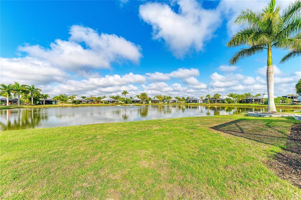 A grassy lawn overlooks a pond surrounded by palm trees and residential houses — 8144 SW BIMINI WAY LOT 64, ARCADIA, FL