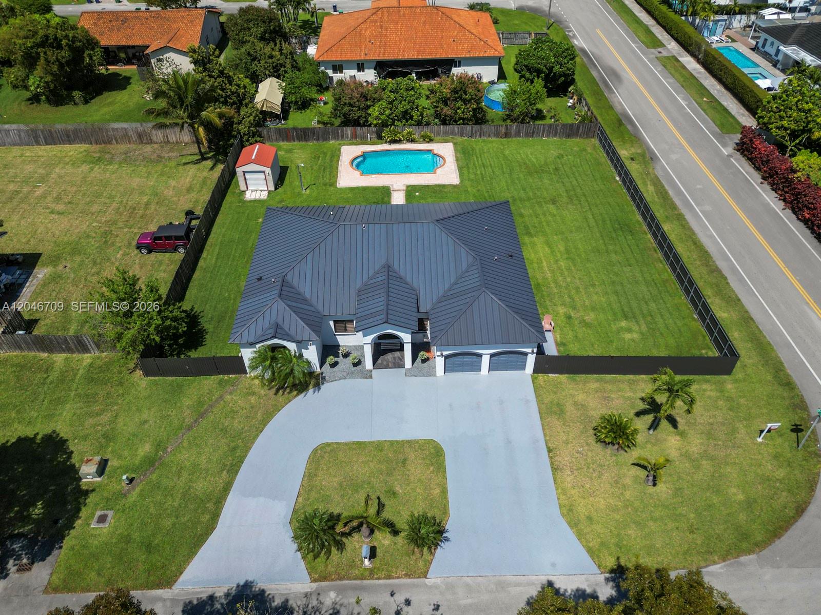 An aerial view shows a house with a dark metal roof, pool, and circular driveway — 13205 SW 218th Ter, Miami FL 33170, MIAMI, FL