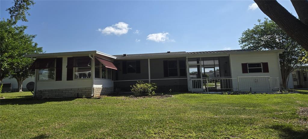 The exterior of a single-story home features white siding, a screened porch, and red awnings — 4122 MYRTLE OAK COURT UNIT 851, ZELLWOOD, FL