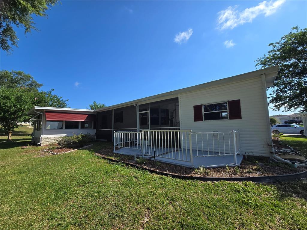 The exterior of a single-story home features light siding, a screened porch, and a small patio — 4122 MYRTLE OAK COURT UNIT 851, ZELLWOOD, FL