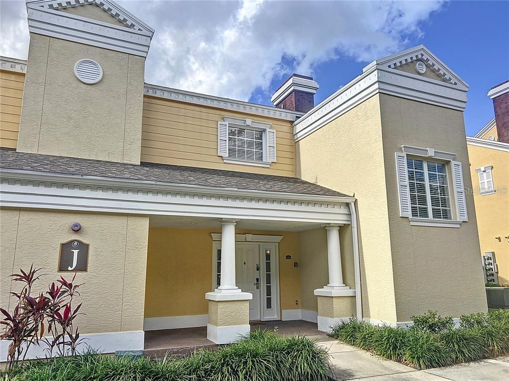 A two-story yellow stucco building features a covered entrance with white columns and shutters — 1328 SEVEN EAGLES COURT, REUNION, FL