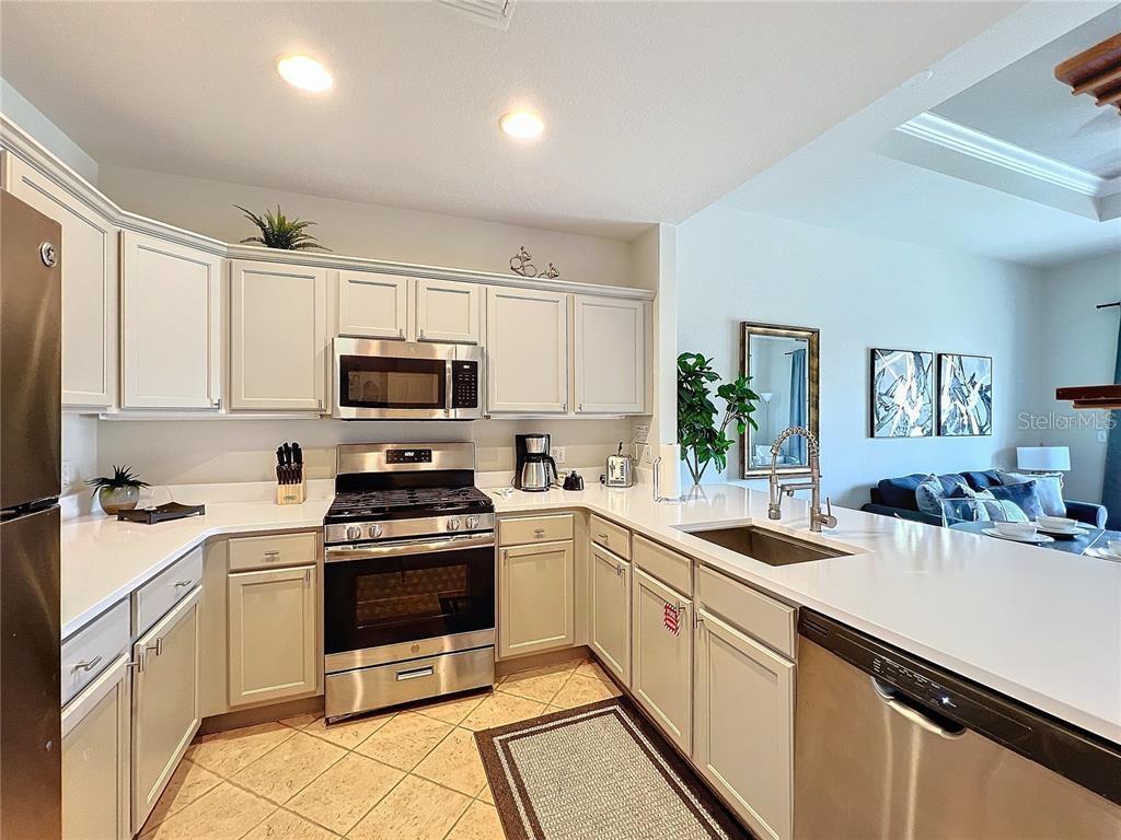 A kitchen with white cabinets, stainless steel appliances, and light countertops features a tile floor — 1328 SEVEN EAGLES COURT, REUNION, FL