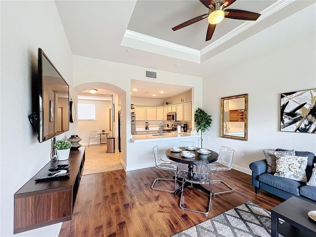 A living room and dining area with hardwood floors, a ceiling fan, and an open kitchen — 1328 SEVEN EAGLES COURT, REUNION, FL