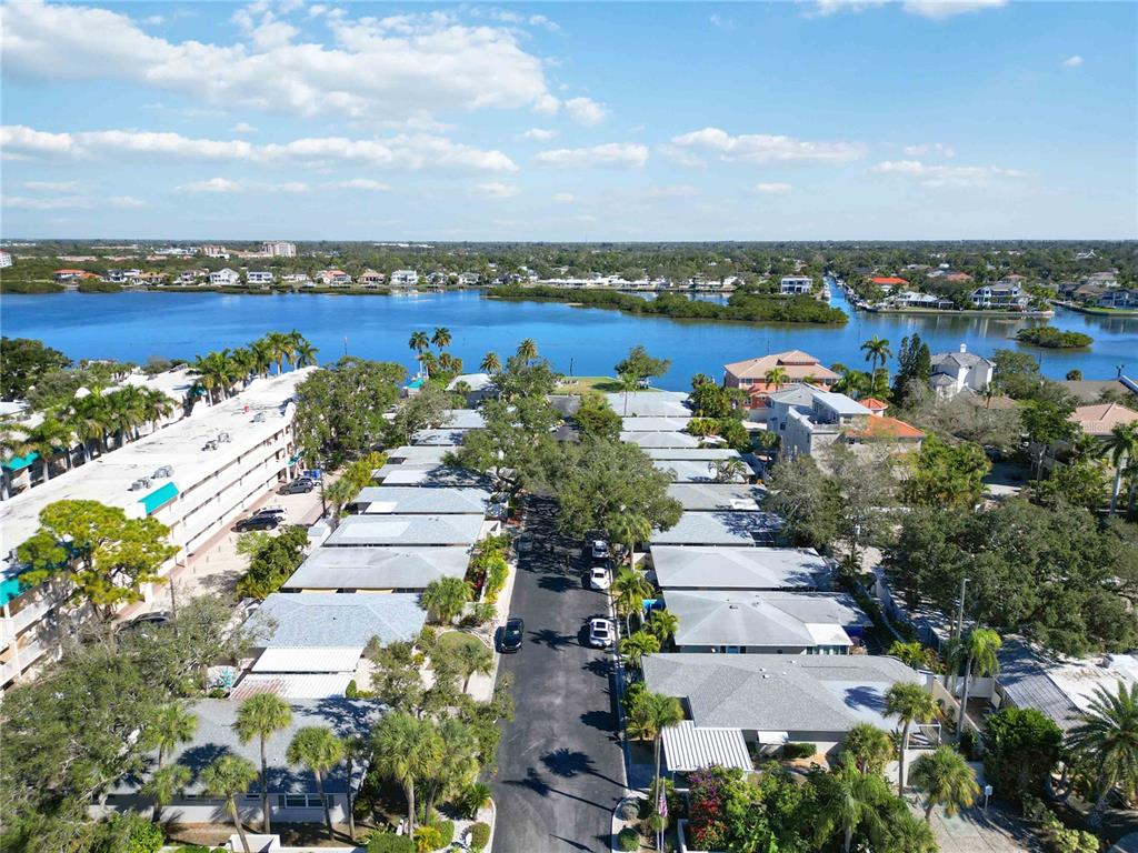 An aerial view shows a residential street lined with single-story homes near a waterfront — 6005 MIDNIGHT PASS ROAD UNIT N4, SARASOTA, FL