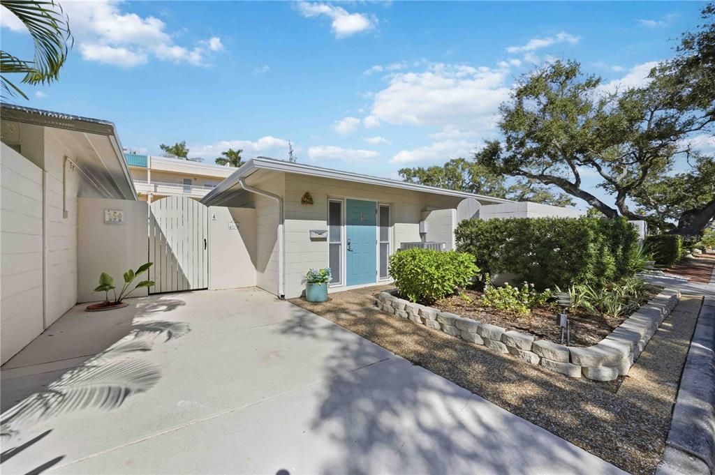 A single-story house with a light blue front door, a concrete driveway, and landscaping — 6005 MIDNIGHT PASS ROAD UNIT N4, SARASOTA, FL
