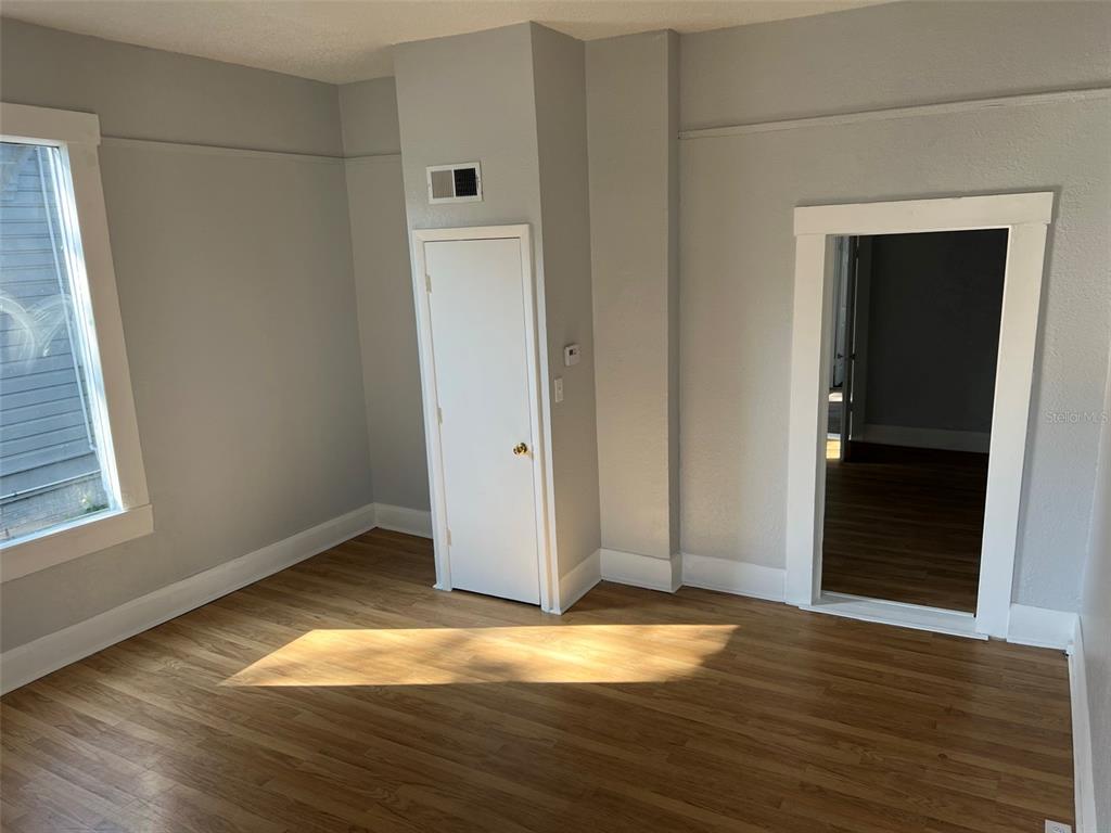 An interior room features light gray walls, wood-look flooring, a white door, and a doorway — 901 PENNSYLVANIA AVENUE UNIT 1, LAKELAND, FL