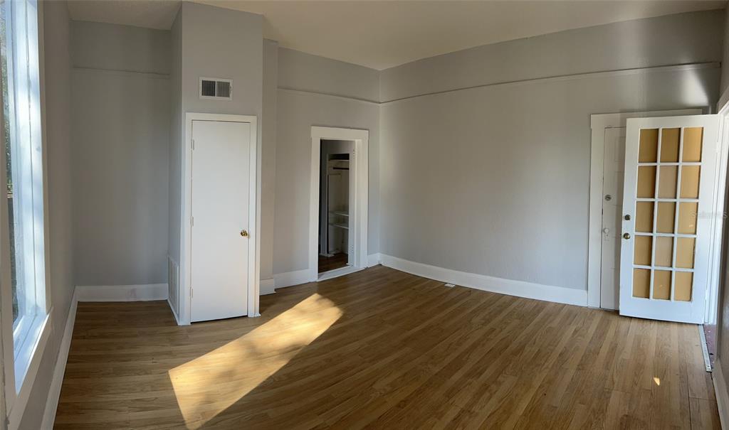 An empty room with light gray walls, hardwood floors, a closet, and a glass-paneled door — 901 PENNSYLVANIA AVENUE UNIT 1, LAKELAND, FL