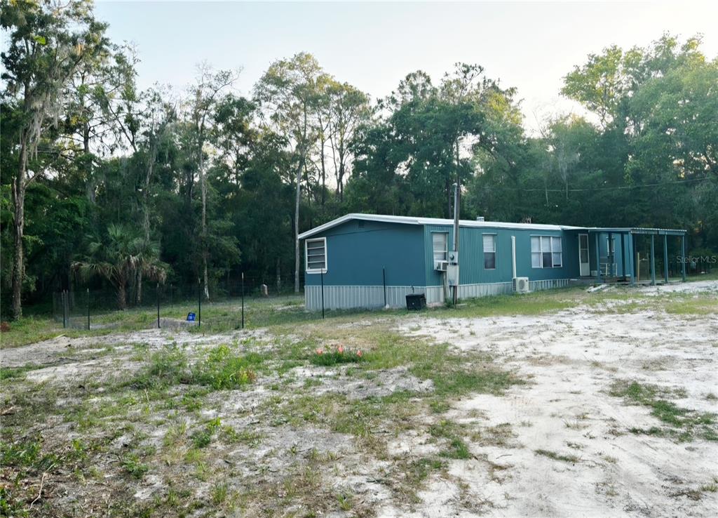 A teal mobile home sits on a sandy lot surrounded by trees — 14207 CAROLINA DOVE ROAD, WEEKI WACHEE, FL