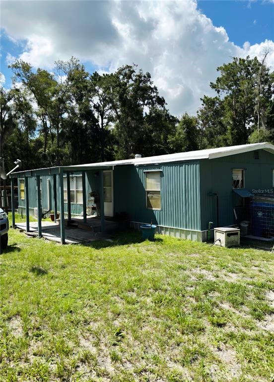 A teal mobile home with a covered wooden porch sits on a grassy lot — 14207 CAROLINA DOVE ROAD, WEEKI WACHEE, FL