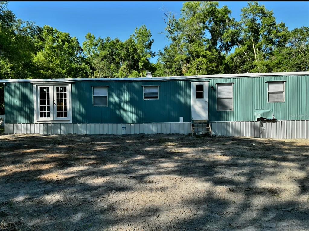 The exterior of a teal mobile home features a set of French doors and windows — 14207 CAROLINA DOVE ROAD, WEEKI WACHEE, FL