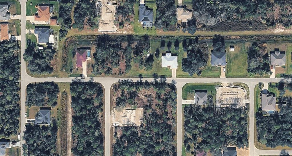 This aerial view shows a residential neighborhood with houses, wooded lots, and paved streets — GREENHOUSE AVENUE, NORTH PORT, FL