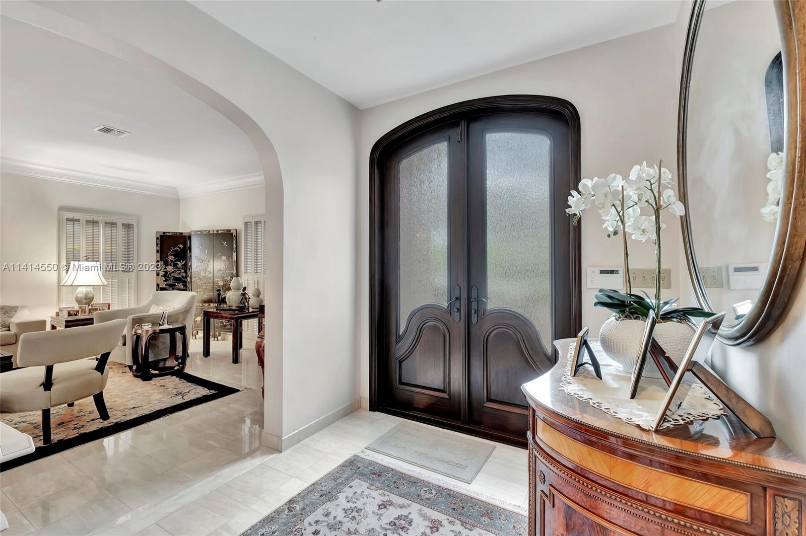 An entryway features a dark wood double door, arched opening, and a marble-topped console table — 4716 University Dr, Coral Gables FL 33146, CORAL GABLES, FL