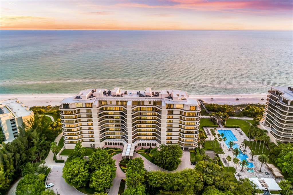 An aerial view shows a multi-story beachfront condominium building with a pool and lush landscaping — 415 L AMBIANCE DRIVE UNIT PH-F, LONGBOAT KEY, FL