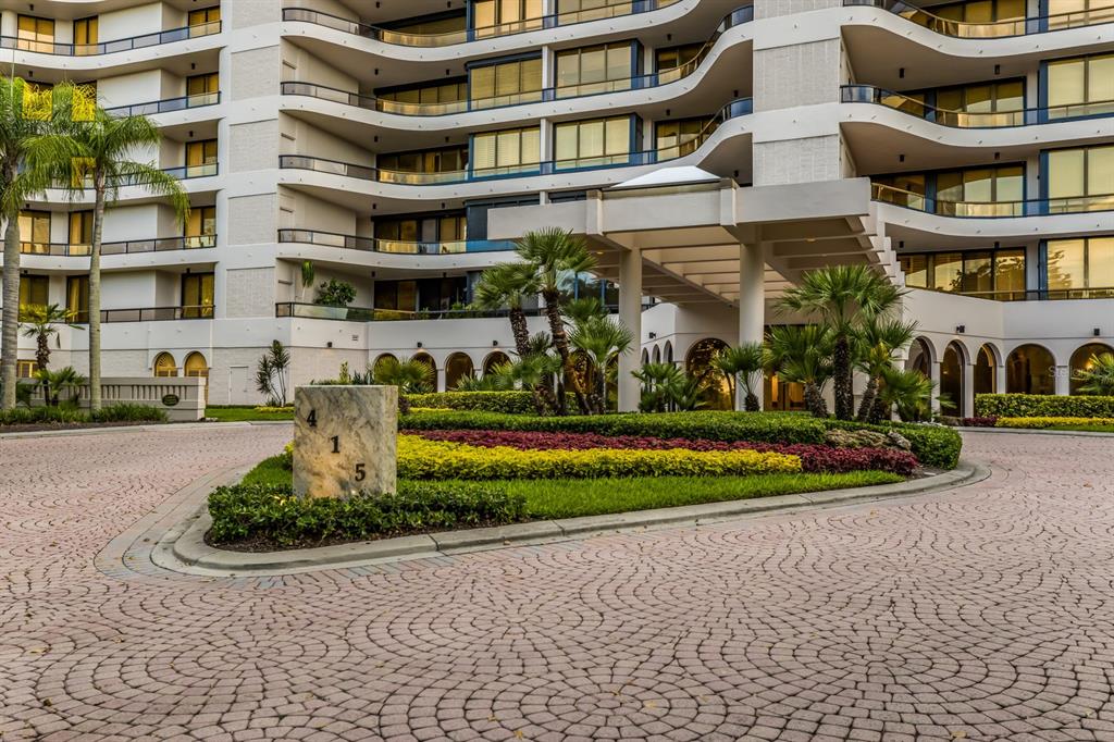 A multi-story residential building features a paved circular driveway and a landscaped entrance island — 415 L AMBIANCE DRIVE UNIT PH-F, LONGBOAT KEY, FL