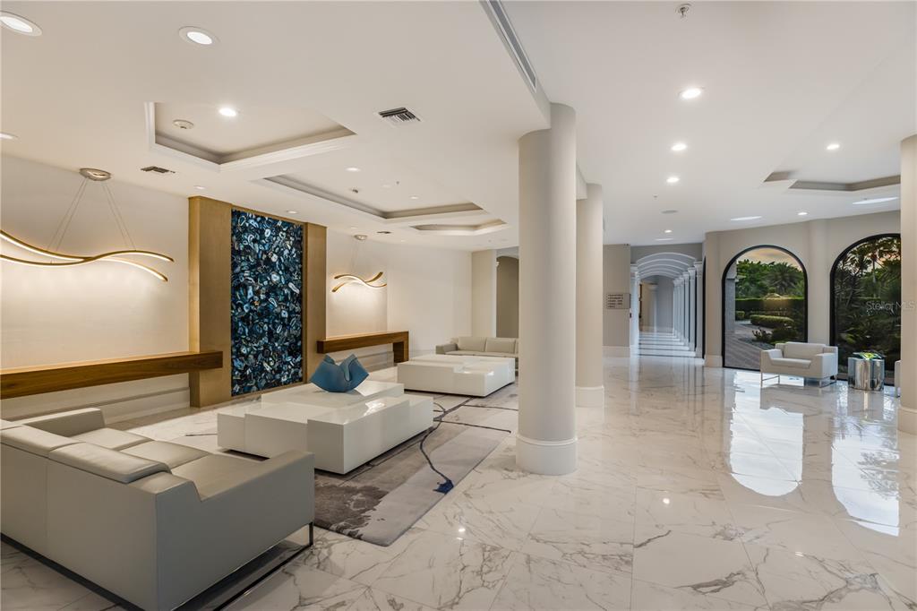 A modern lobby features marble floors, white sofas, and a decorative blue stone accent wall — 415 L AMBIANCE DRIVE UNIT PH-F, LONGBOAT KEY, FL