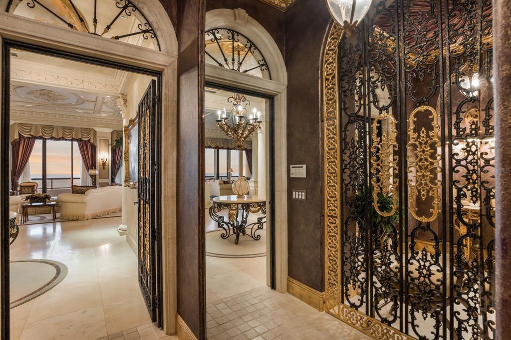 An ornate hallway features arched doorways, decorative iron gates, and marble flooring — 415 L AMBIANCE DRIVE UNIT PH-F, LONGBOAT KEY, FL