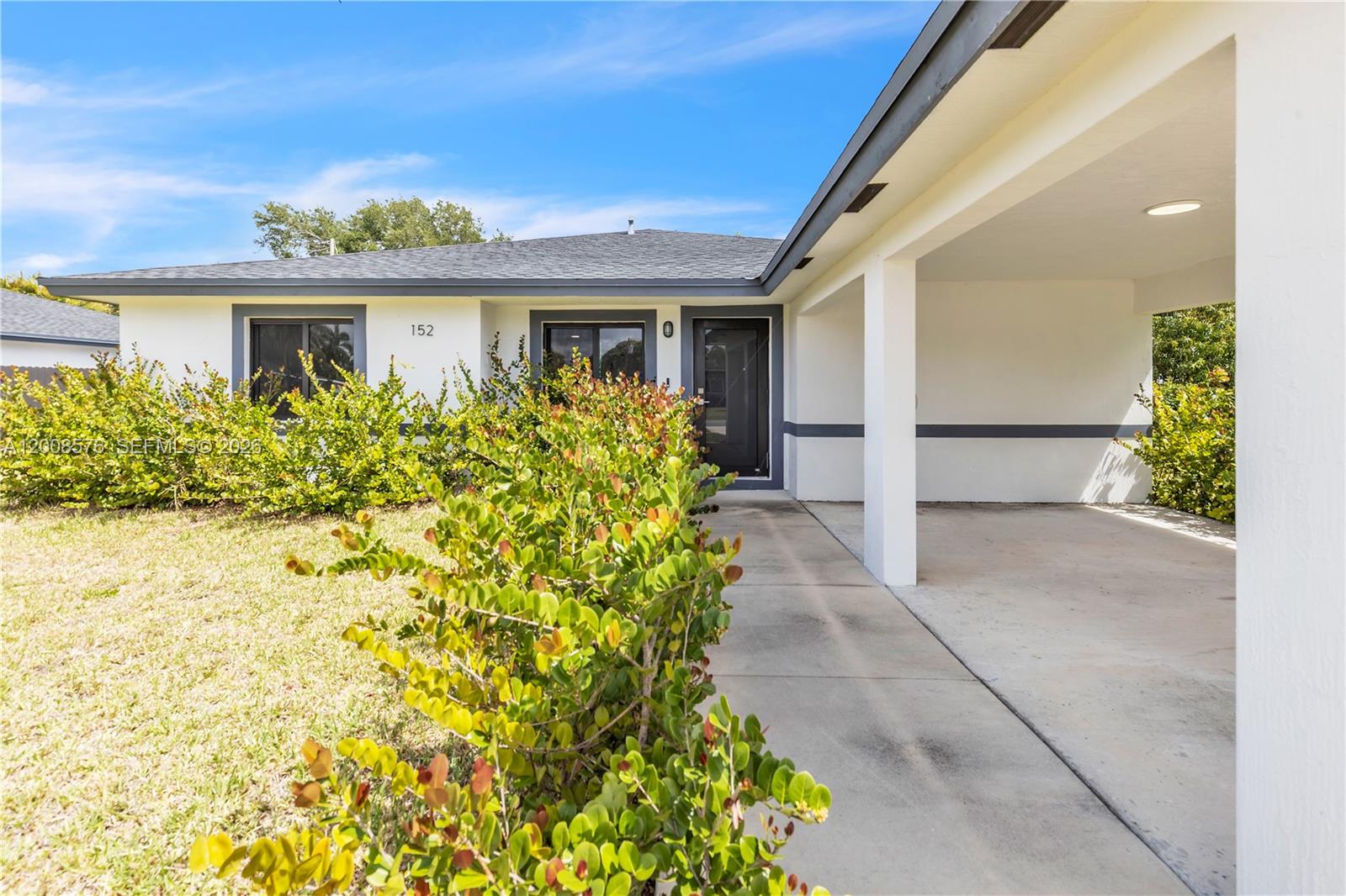 A single-story house features a white exterior, a covered carport, and a front walkway — 152 NW 18 St, Homestead FL 33030, HOMESTEAD, FL