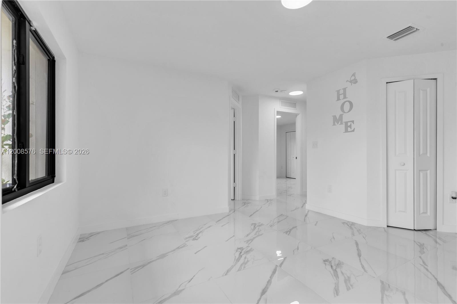 A bright room features white walls, marble-patterned tile flooring, and a white bi-fold closet door — 152 NW 18 St, Homestead FL 33030, HOMESTEAD, FL