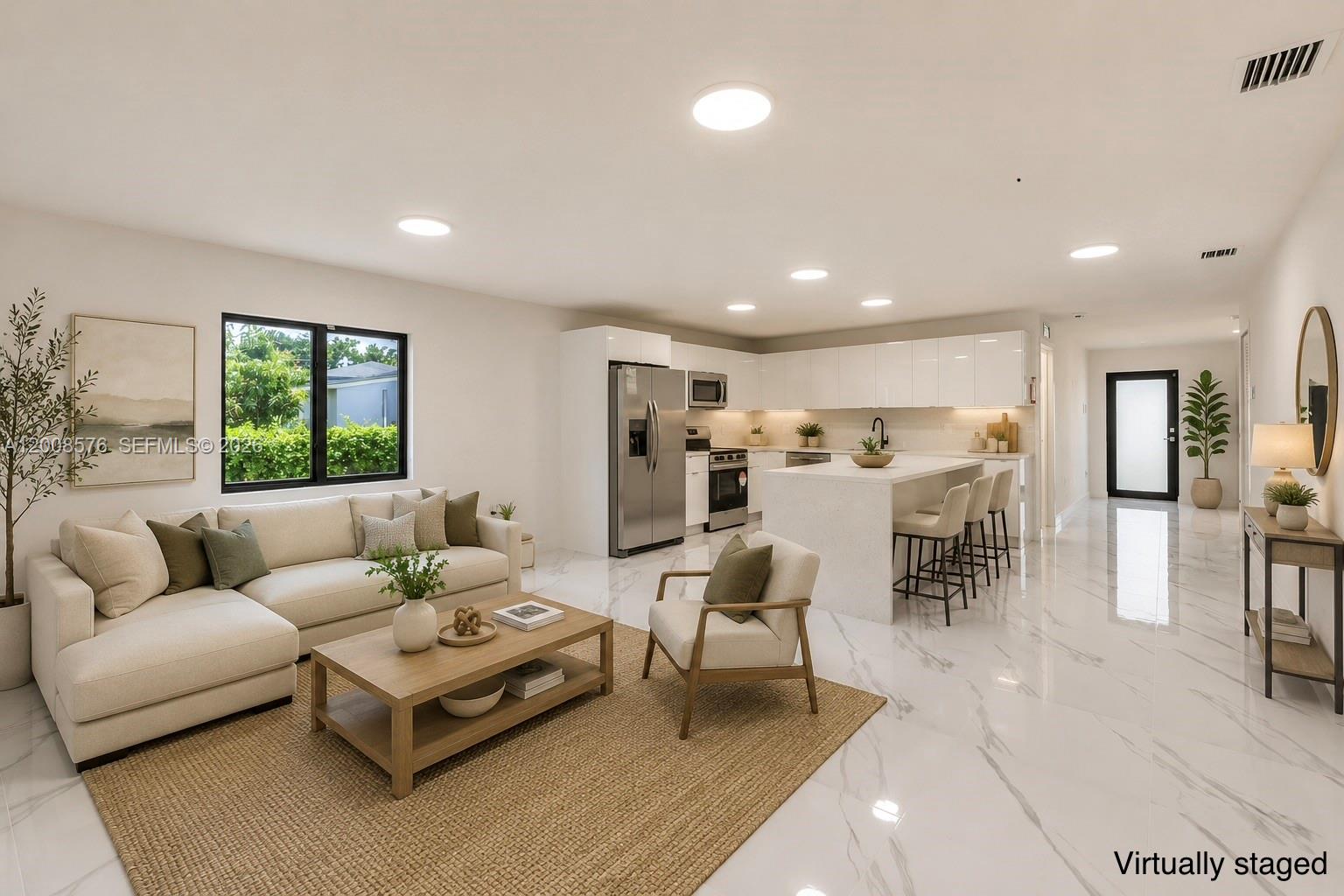 This virtually staged open-concept living room and kitchen features white marble floors and cabinetry — 152 NW 18 St, Homestead FL 33030, HOMESTEAD, FL