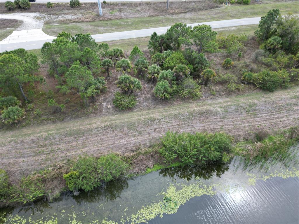 An aerial view shows a wooded lot bordering a road and a small pond — S RAINTREE BOULEVARD, NORTH PORT, FL
