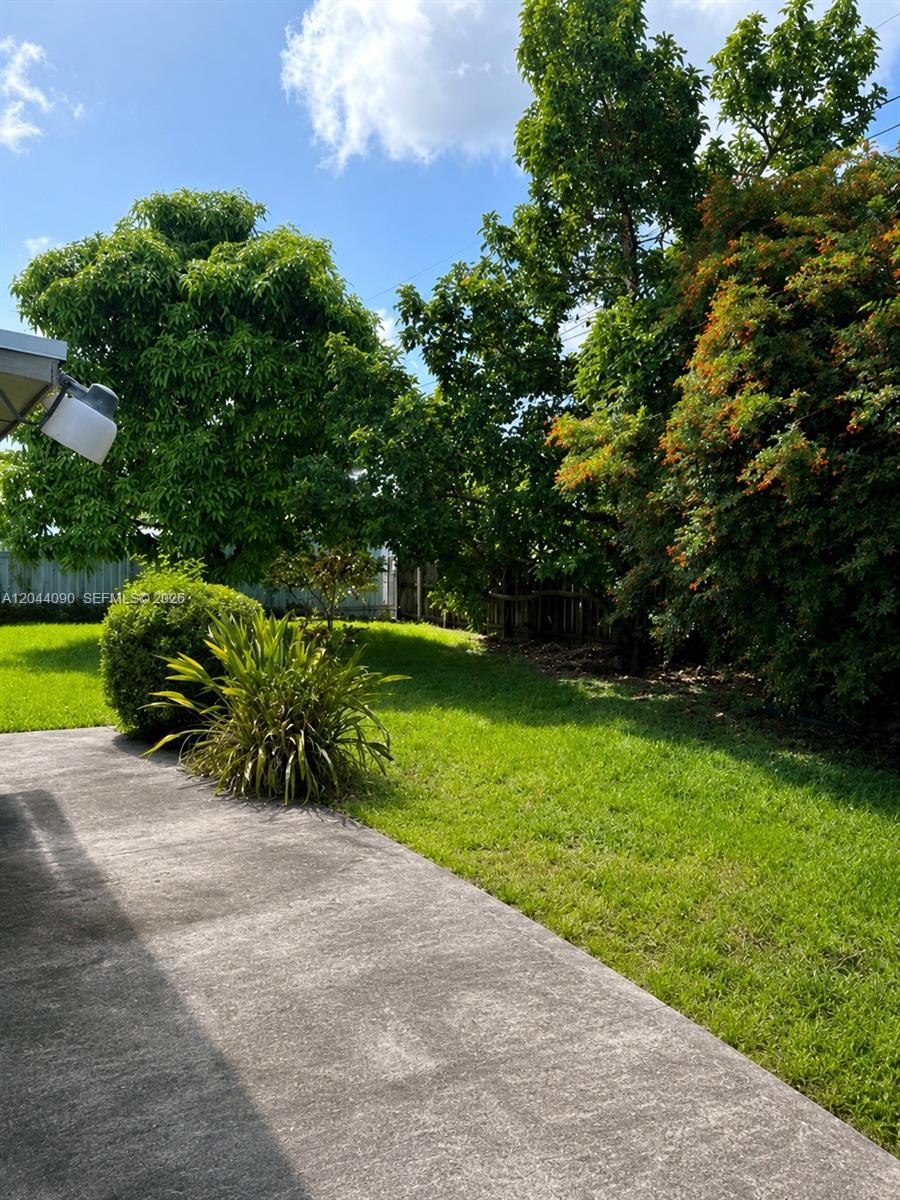 A concrete patio overlooks a grassy backyard with mature trees and shrubs — 11832 SW 185th Ter, Miami FL 33177, MIAMI, FL