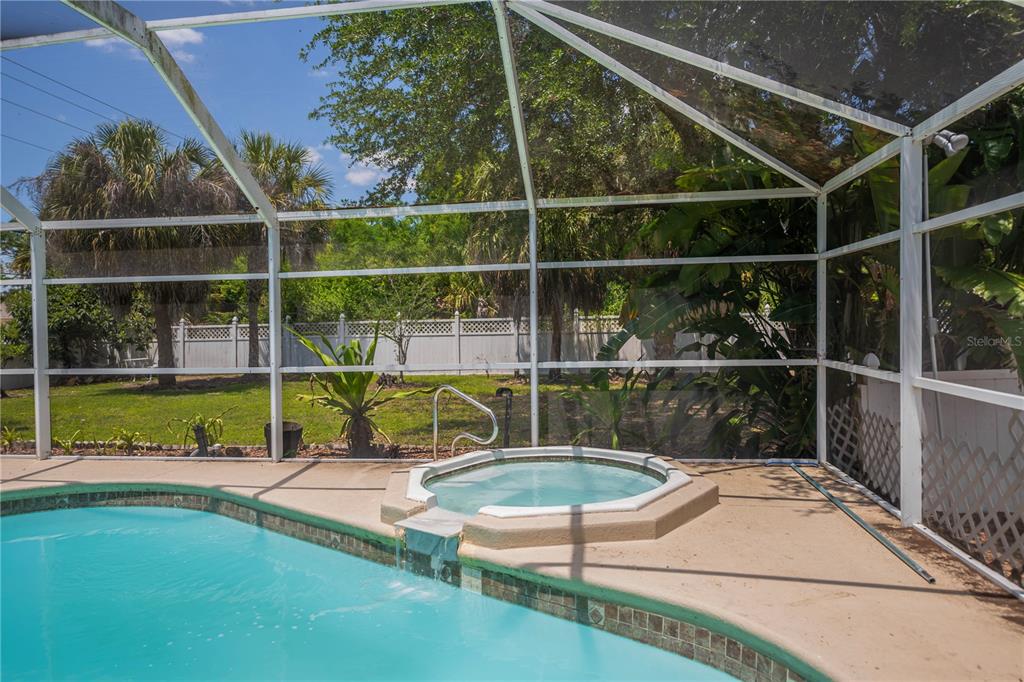 A screened-in pool area features a raised hot tub spilling into a swimming pool — 2618 8TH STREET W, LEHIGH ACRES, FL