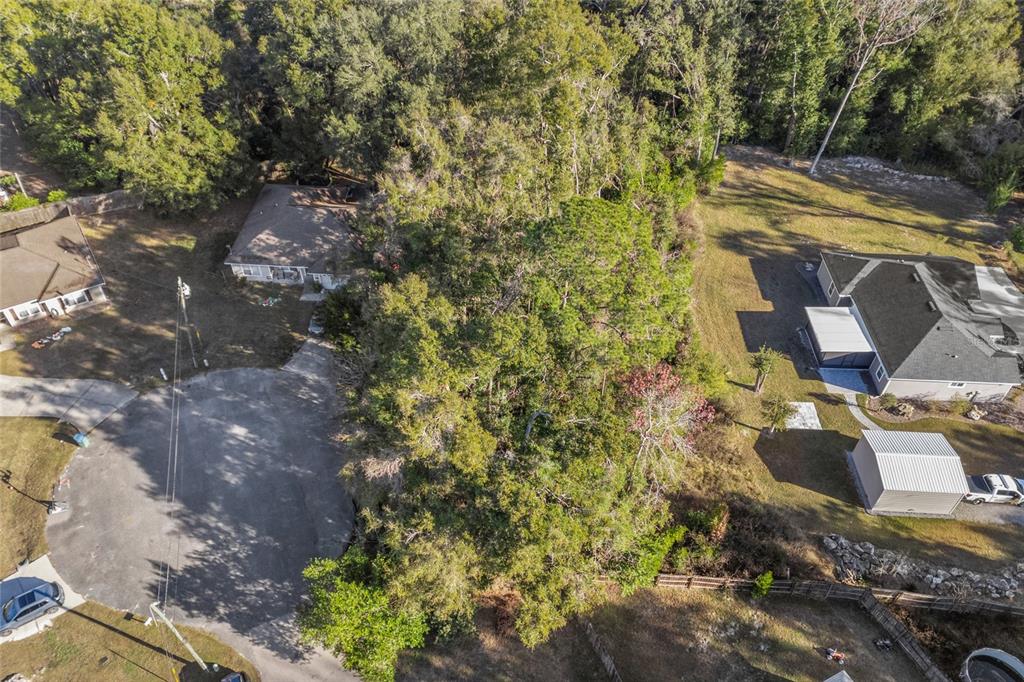 An aerial view shows a wooded lot situated between two residential houses and a cul-de-sac — 00 NW 236TH WAY, HIGH SPRINGS, FL