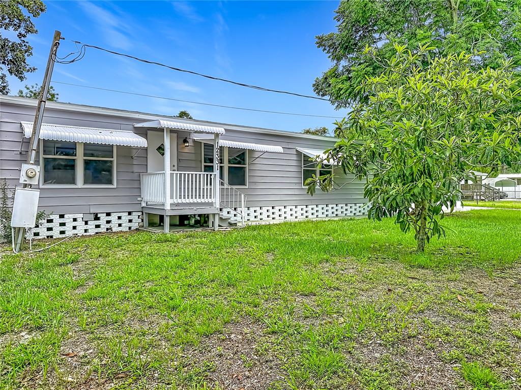 A single-story gray mobile home features a small front porch and white lattice skirting — 12331 PARKWOOD STREET, HUDSON, FL