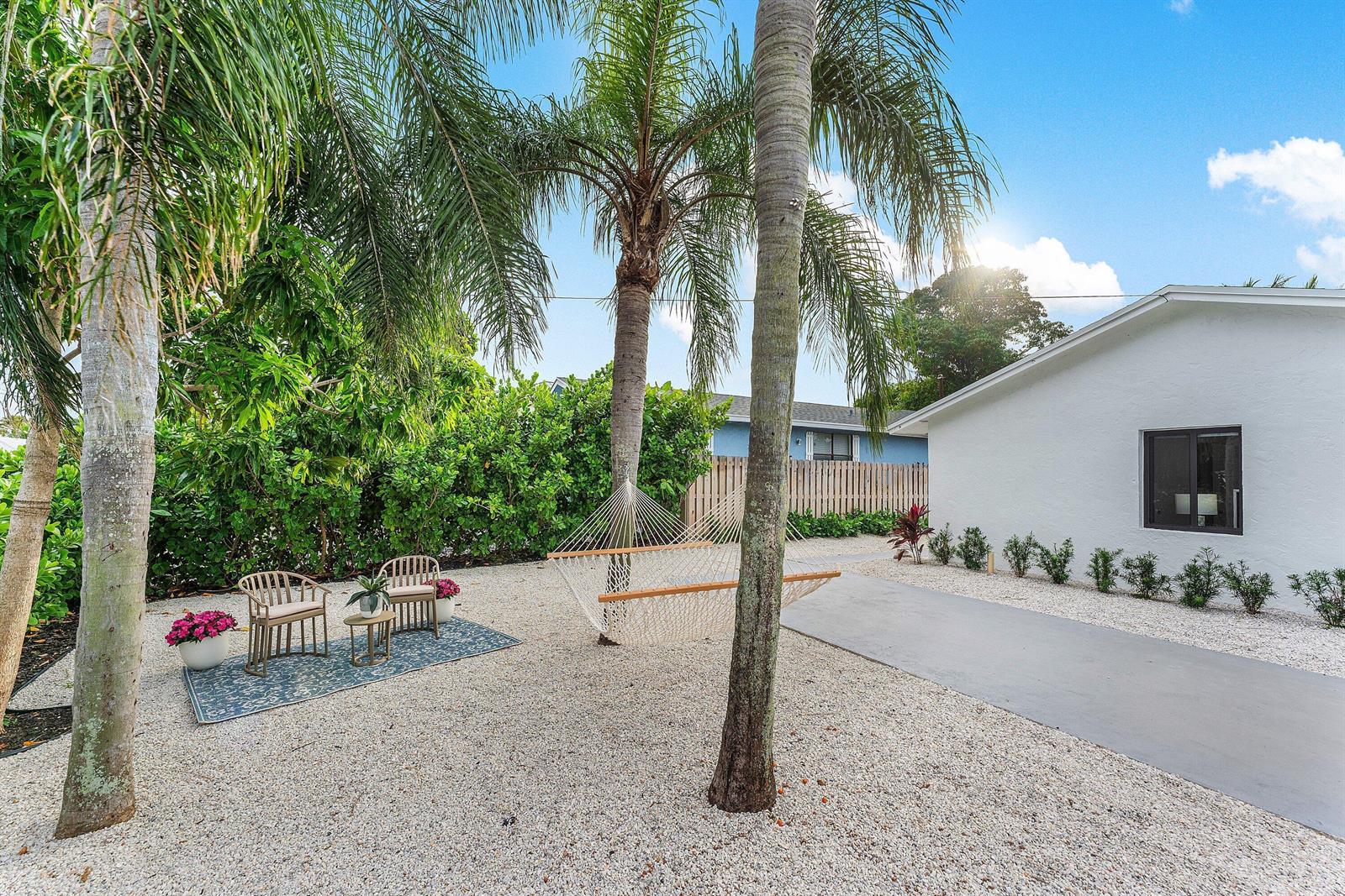 A gravel yard features a hammock, two chairs on a rug, and palm trees — 608 SE 2nd Avenue, Delray Beach FL 33483, DELRAY BEACH, FL