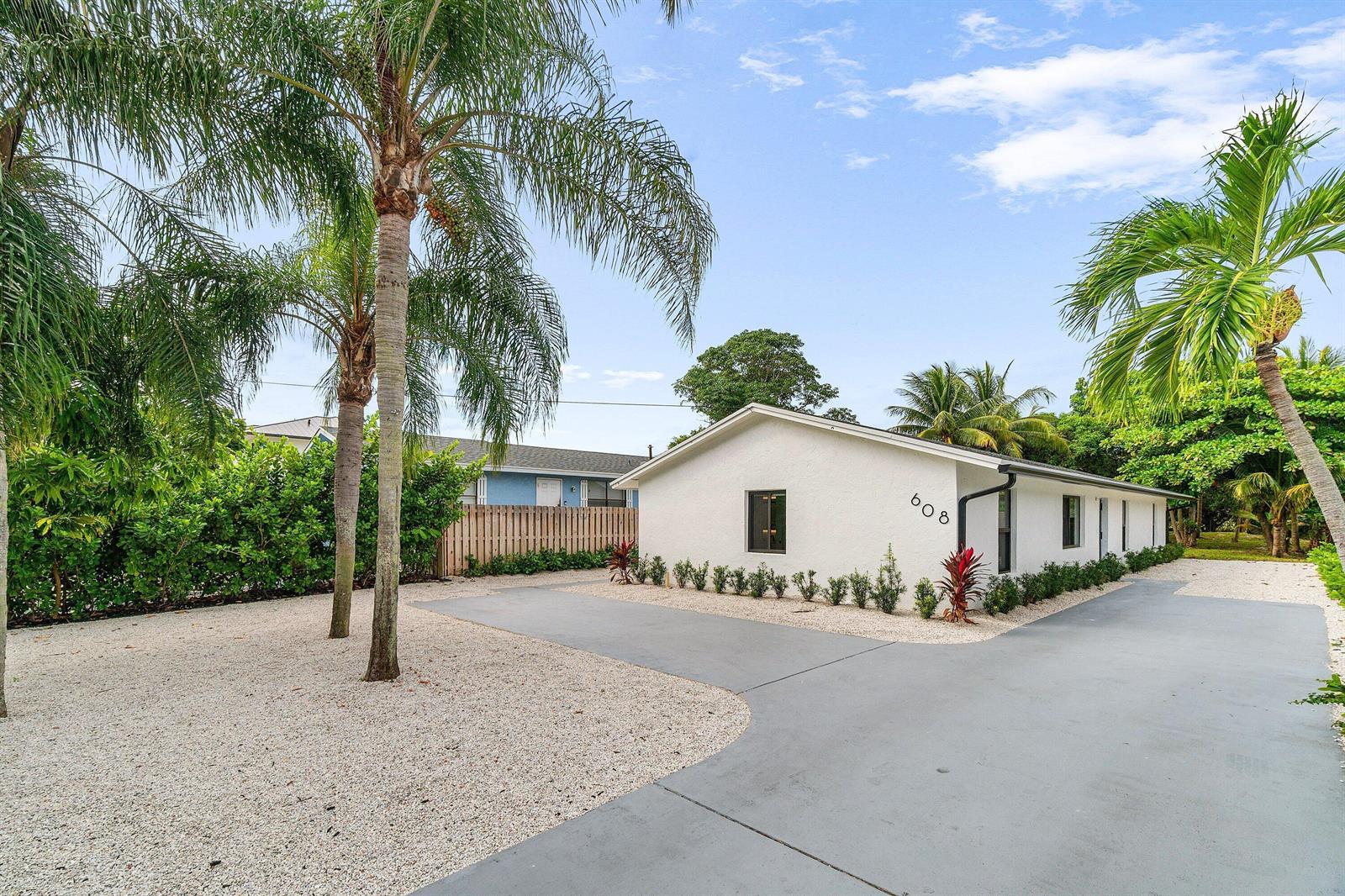 A white single-story house with a gray driveway and gravel landscaping under a blue sky — 608 SE 2nd Avenue, Delray Beach FL 33483, DELRAY BEACH, FL