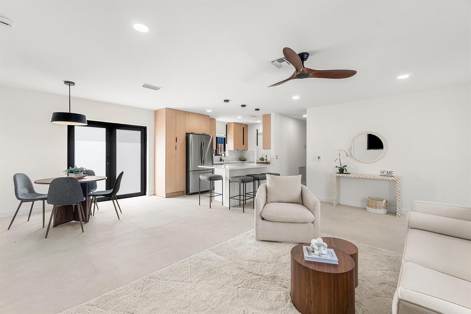 An open-concept living and dining area features light tile floors, modern cabinetry, and neutral furniture — 608 SE 2nd Avenue, Delray Beach FL 33483, DELRAY BEACH, FL