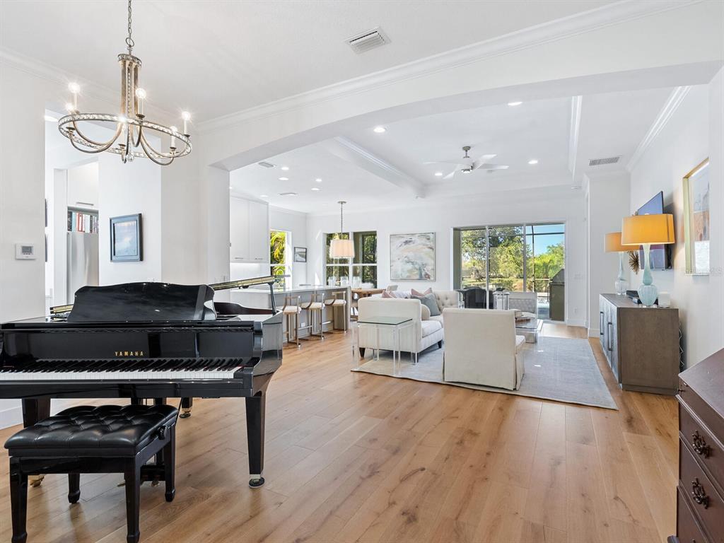 An open-concept living room and kitchen featuring white cabinetry, wood flooring, and a sliding door — 12129 THORNHILL COURT, LAKEWOOD RANCH, FL