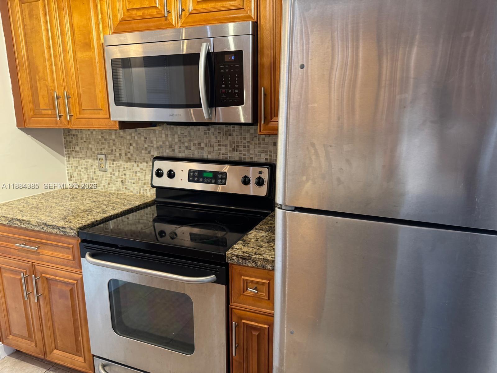 A kitchen features stainless steel appliances, wood cabinets, and a granite countertop — 2471 SW 82nd Ave # 108, Davie FL 33324, DAVIE, FL