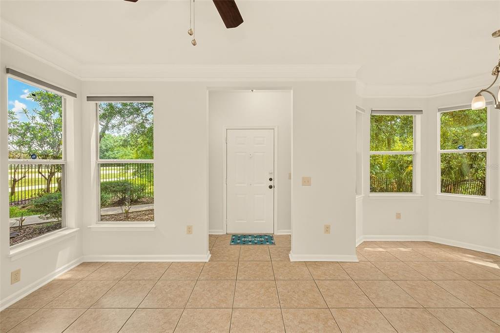A bright room with beige tile flooring, white walls, and windows looking out to greenery — 18138 VILLA CREEK DRIVE UNIT 18138, TAMPA, FL