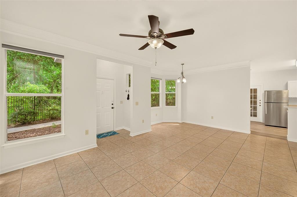 An open-concept dining area with tile flooring, a ceiling fan, and a view of trees — 18138 VILLA CREEK DRIVE UNIT 18138, TAMPA, FL