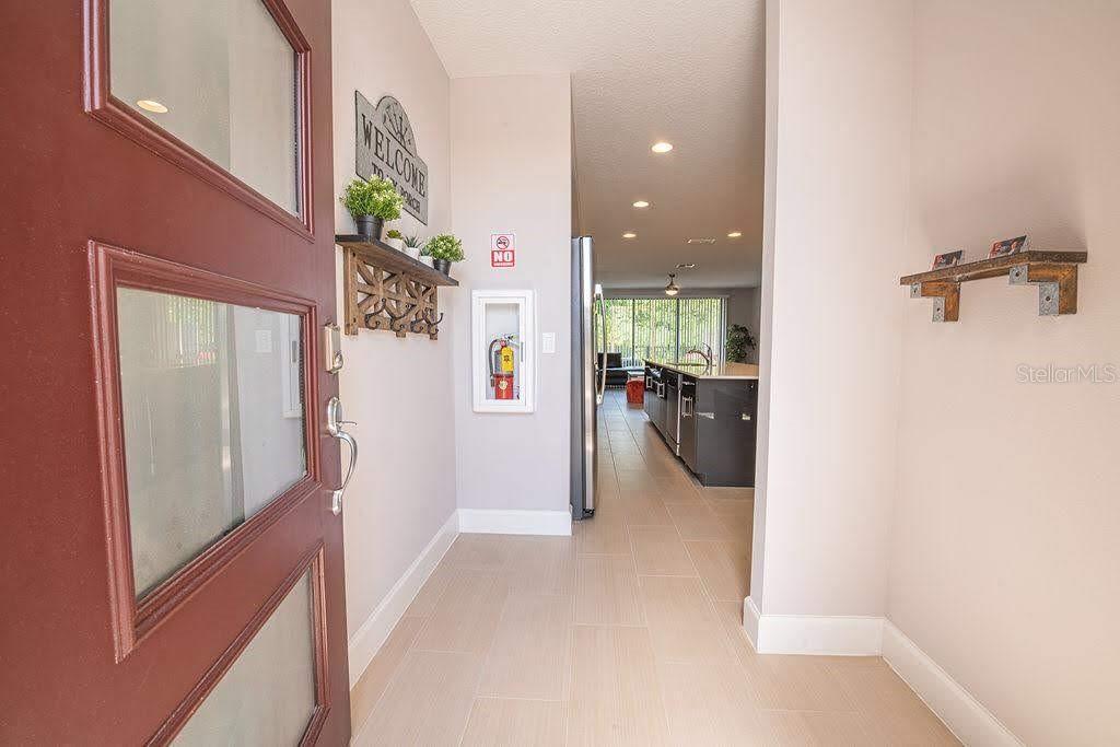 An entryway with tile flooring leads into an open-concept kitchen with a large island — 4730 TERRA ESMERALDA DRIVE, KISSIMMEE, FL