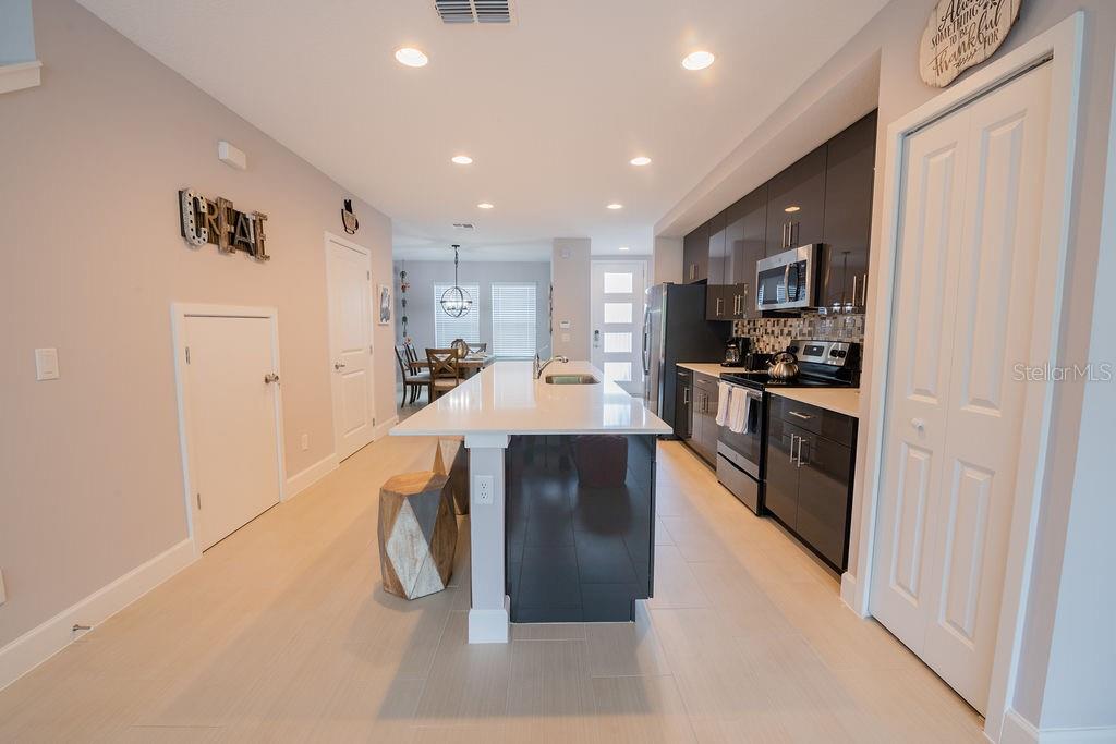 A kitchen features a white island, dark cabinetry, stainless steel appliances, and light tile flooring — 4730 TERRA ESMERALDA DRIVE, KISSIMMEE, FL