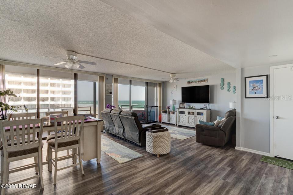 An open-concept living and dining area features wood-look flooring, a ceiling fan, and ocean views — 2828 N ATLANTIC AVENUE UNIT 303, DAYTONA BEACH, FL