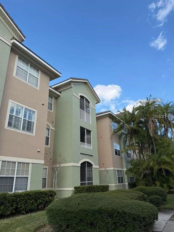 A multi-story apartment building with tan and green stucco walls and manicured landscaping — 4865 CYPRESS WOODS DRIVE UNIT 2302, ORLANDO, FL